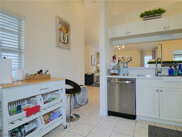 kitchen featuring dishwasher, white cabinets, light tile patterned floors, and sink