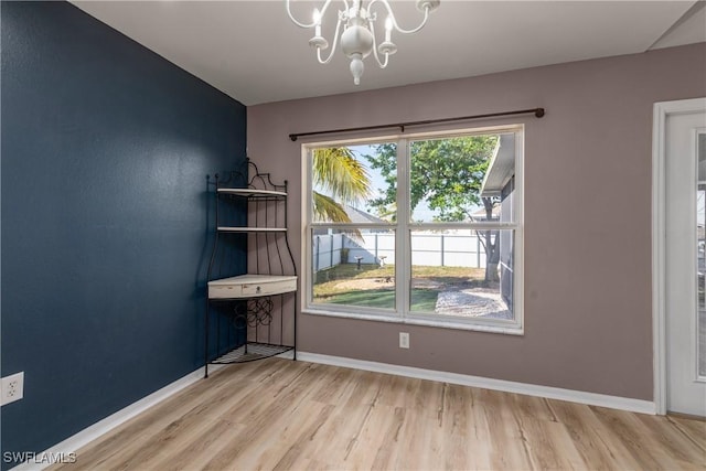 unfurnished room featuring a notable chandelier and wood-type flooring