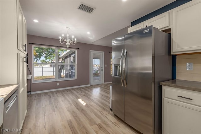 kitchen with stainless steel appliances, a notable chandelier, light hardwood / wood-style floors, pendant lighting, and white cabinets