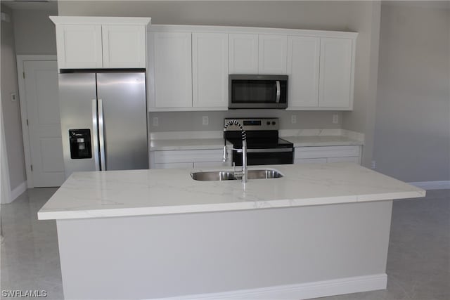 kitchen with light stone countertops, stainless steel appliances, an island with sink, white cabinets, and sink