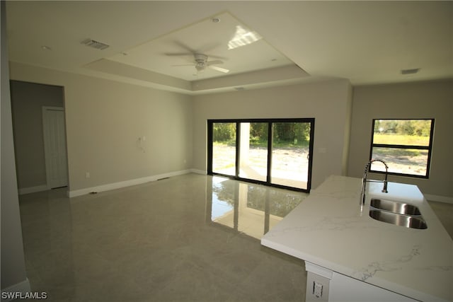 empty room featuring ceiling fan, sink, and a tray ceiling