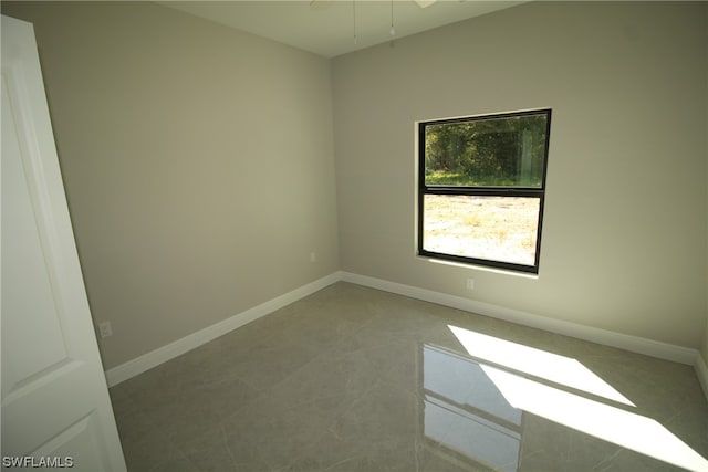 tiled empty room featuring ceiling fan