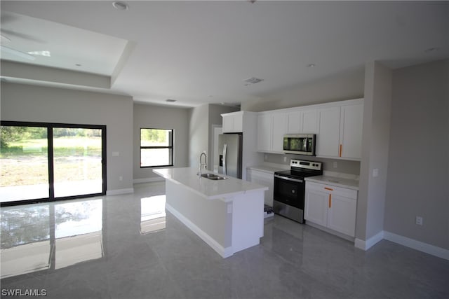 kitchen with a kitchen island with sink, white cabinets, tile floors, appliances with stainless steel finishes, and sink