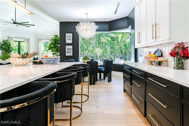 kitchen with white cabinetry, light countertops, tasteful backsplash, and light wood finished floors