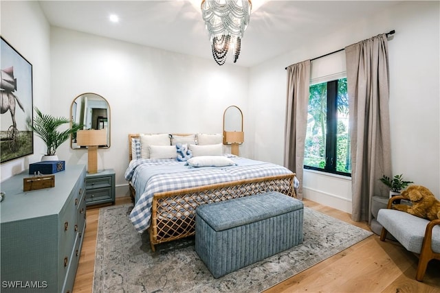 bedroom featuring recessed lighting, baseboards, light wood-style floors, and an inviting chandelier