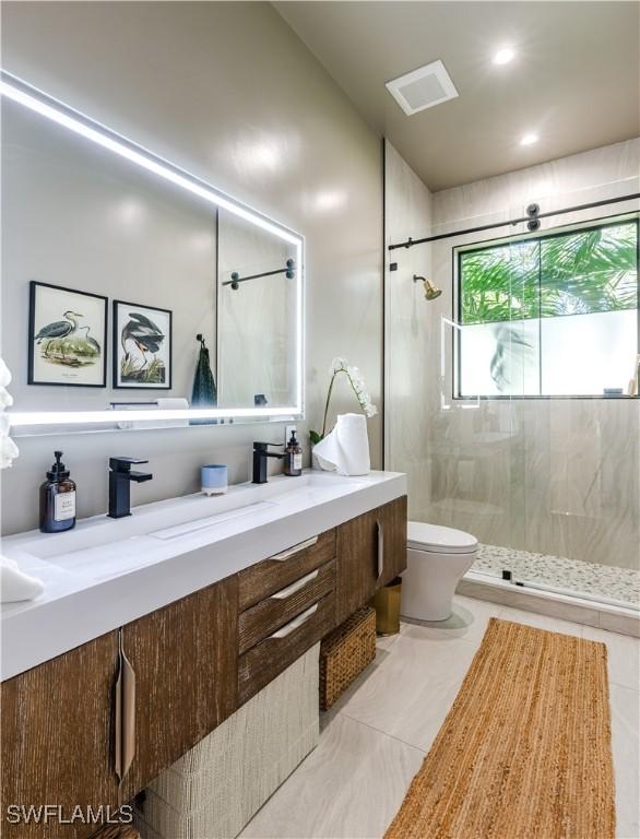 bathroom featuring visible vents, toilet, a stall shower, and vanity