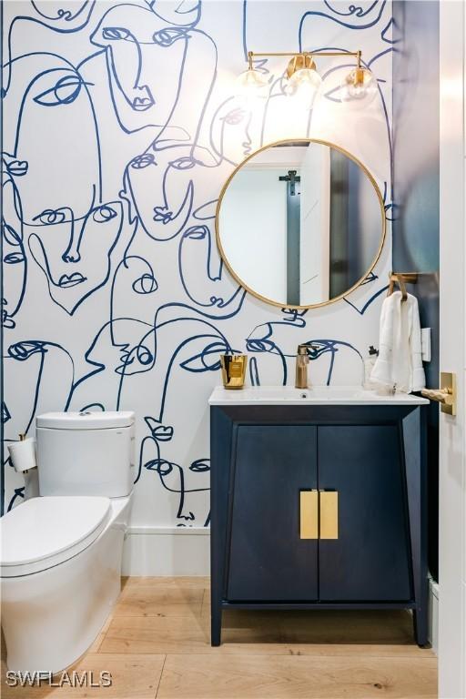 bathroom with toilet, vanity, and wood finished floors