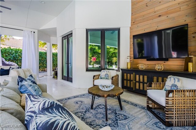 living room with high vaulted ceiling, wood walls, and finished concrete flooring