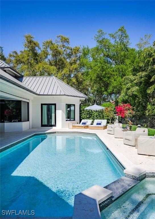 view of pool featuring an outdoor living space, a pool with connected hot tub, and a patio