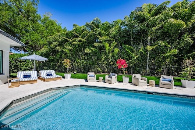 pool with a patio area and fence
