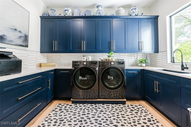 laundry area with washing machine and dryer, cabinet space, light wood-style floors, and a sink