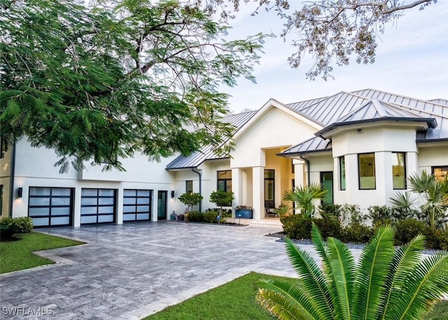 view of front of property with metal roof, decorative driveway, stucco siding, and a standing seam roof
