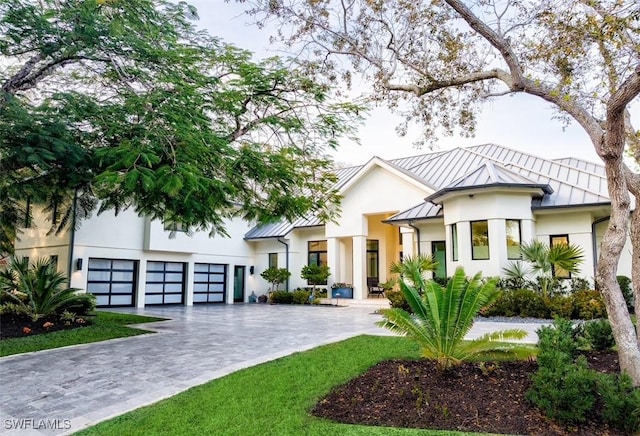 view of front of home with metal roof, decorative driveway, stucco siding, and a standing seam roof