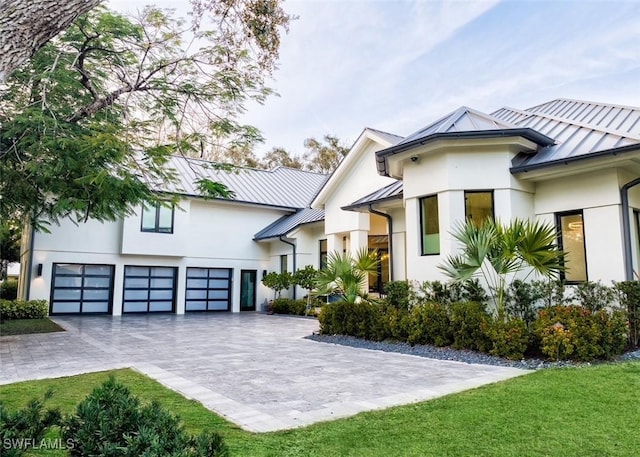 view of front of property with a standing seam roof, decorative driveway, metal roof, and stucco siding