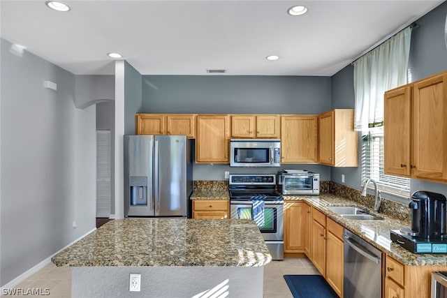 kitchen featuring a center island, sink, light tile patterned floors, and stainless steel appliances