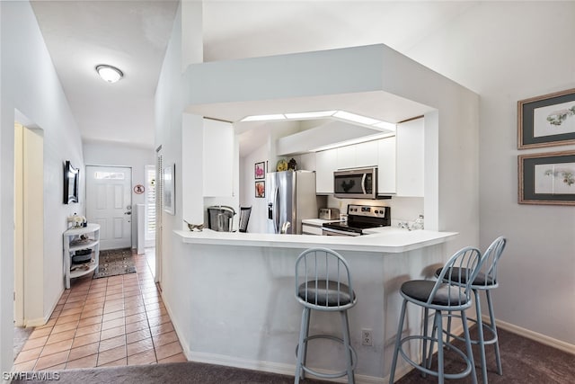 kitchen with a kitchen breakfast bar, stainless steel appliances, light tile flooring, kitchen peninsula, and white cabinetry