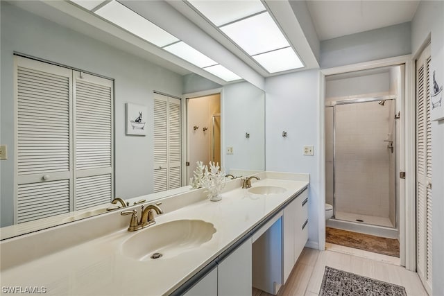 bathroom featuring walk in shower, tile flooring, large vanity, dual sinks, and toilet