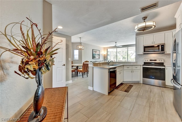 kitchen with white cabinets, kitchen peninsula, appliances with stainless steel finishes, sink, and ceiling fan