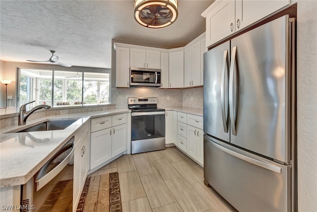 kitchen featuring white cabinets, appliances with stainless steel finishes, sink, ceiling fan, and a textured ceiling