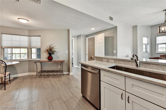 kitchen with dishwasher, a textured ceiling, light stone counters, white cabinets, and sink