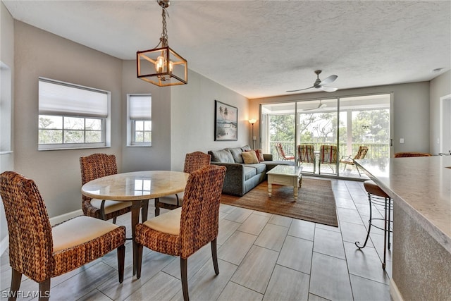 dining room with ceiling fan with notable chandelier and a textured ceiling