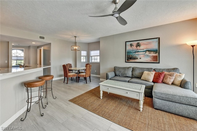 living room featuring ceiling fan and a textured ceiling