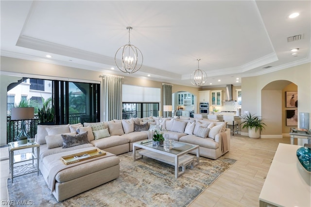 tiled living room featuring a notable chandelier, a raised ceiling, and a healthy amount of sunlight