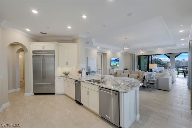 kitchen featuring appliances with stainless steel finishes, white cabinetry, light stone counters, and sink