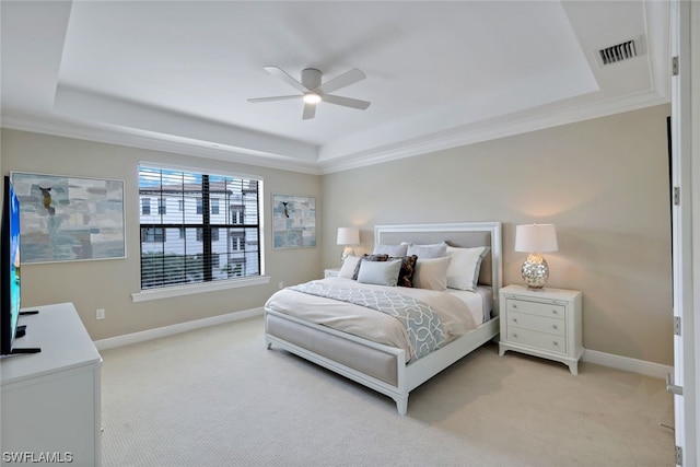 bedroom with light carpet, crown molding, ceiling fan, and a tray ceiling