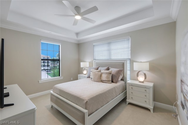 bedroom with light carpet, ornamental molding, ceiling fan, and a tray ceiling