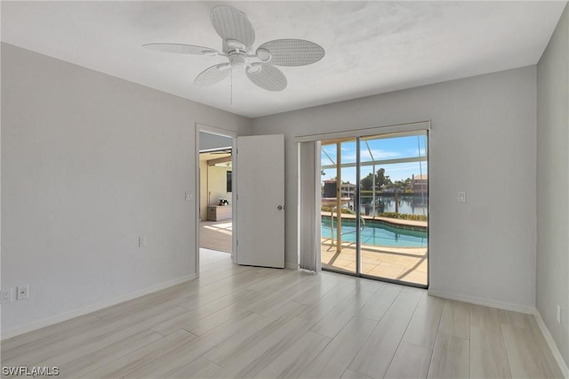 spare room featuring a water view, ceiling fan, and light hardwood / wood-style flooring