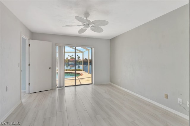 empty room with a water view, light hardwood / wood-style flooring, and ceiling fan