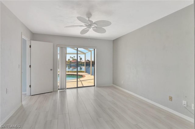 unfurnished room featuring a water view, ceiling fan, and light wood-type flooring