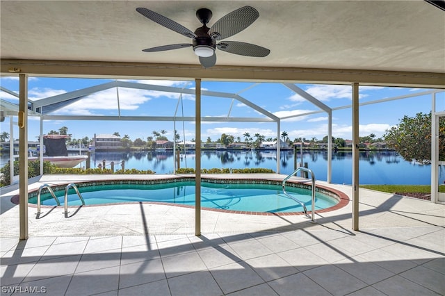 view of swimming pool featuring glass enclosure, ceiling fan, a patio area, and a water view