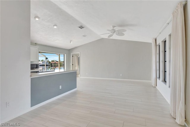 unfurnished living room with ceiling fan, vaulted ceiling, and light wood-type flooring