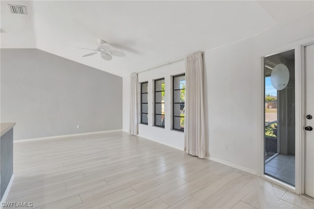 spare room with light wood-type flooring, vaulted ceiling, and ceiling fan