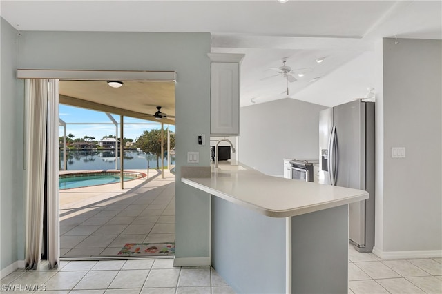 kitchen featuring ceiling fan, light tile patterned floors, kitchen peninsula, a water view, and appliances with stainless steel finishes