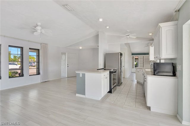 kitchen with lofted ceiling, white cabinetry, a kitchen island, ceiling fan, and stainless steel electric stove