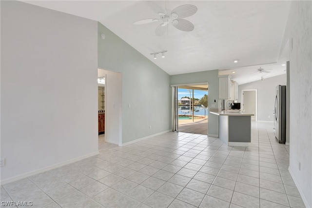 kitchen with lofted ceiling, ceiling fan, stainless steel fridge, light tile patterned floors, and white cabinetry