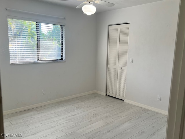 unfurnished bedroom featuring ceiling fan, a closet, and light wood-type flooring