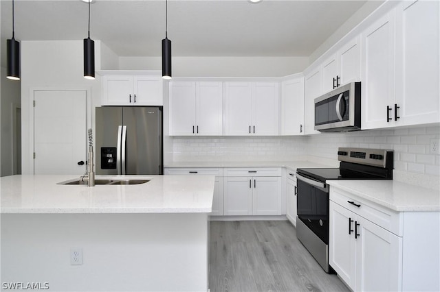 kitchen with decorative light fixtures, a center island with sink, white cabinetry, light stone countertops, and stainless steel appliances