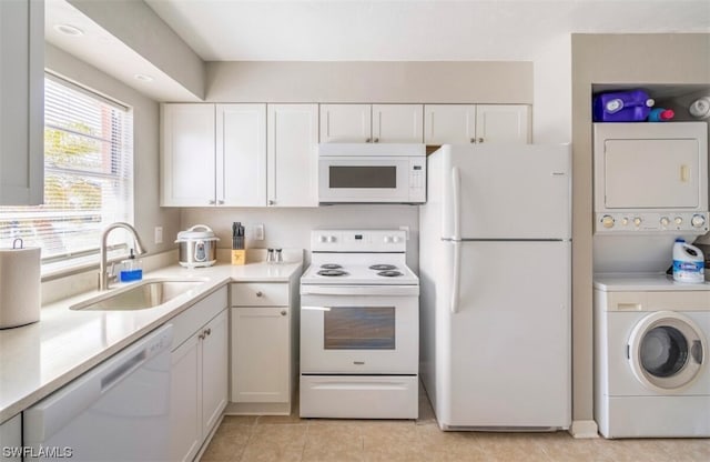 kitchen with light tile floors, stacked washer / dryer, white appliances, white cabinetry, and sink