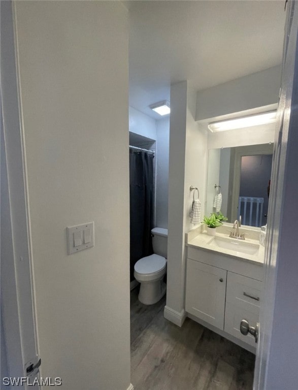 bathroom with toilet, vanity with extensive cabinet space, and hardwood / wood-style flooring