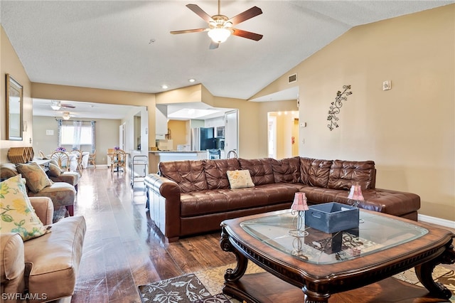 living room featuring lofted ceiling, ceiling fan, dark wood-type flooring, and a textured ceiling