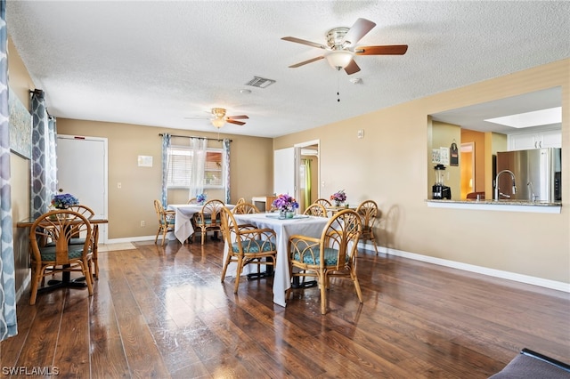 dining area featuring dark wood-type flooring, ceiling fan, and a textured ceiling