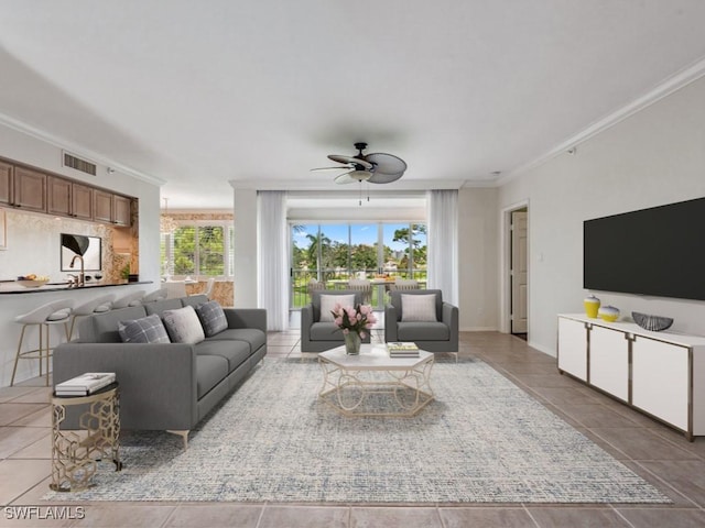 tiled living room with ceiling fan, a healthy amount of sunlight, and ornamental molding