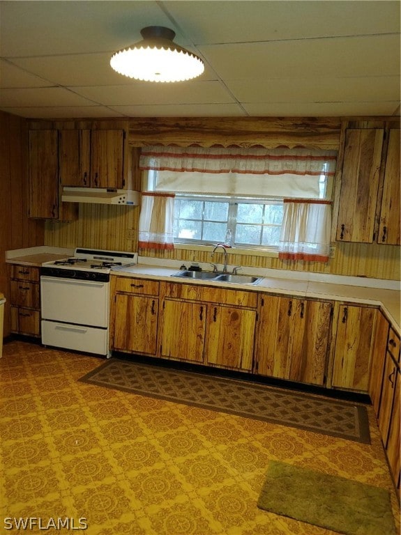 kitchen with sink, white range with electric cooktop, a paneled ceiling, and wood walls