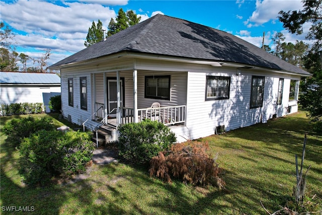 rear view of property featuring a yard and covered porch