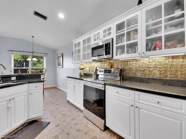 kitchen featuring white cabinets, vaulted ceiling, stainless steel appliances, and an inviting chandelier