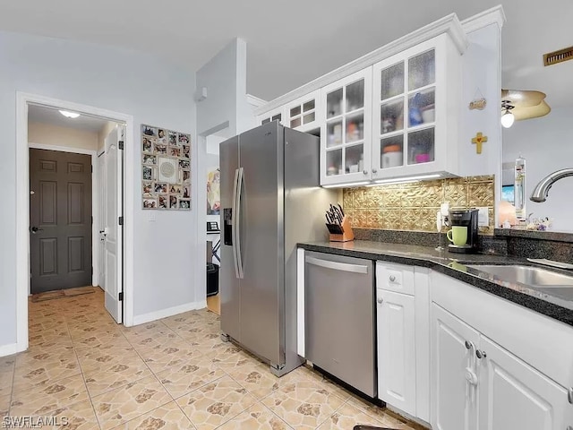 kitchen featuring appliances with stainless steel finishes, sink, light tile floors, white cabinets, and tasteful backsplash